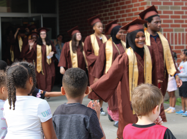 elementary students cheering for high school graduates